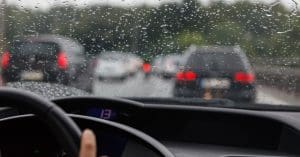 Auto accident lawyer referral hotline. Photo depicts a car driving in the rain.