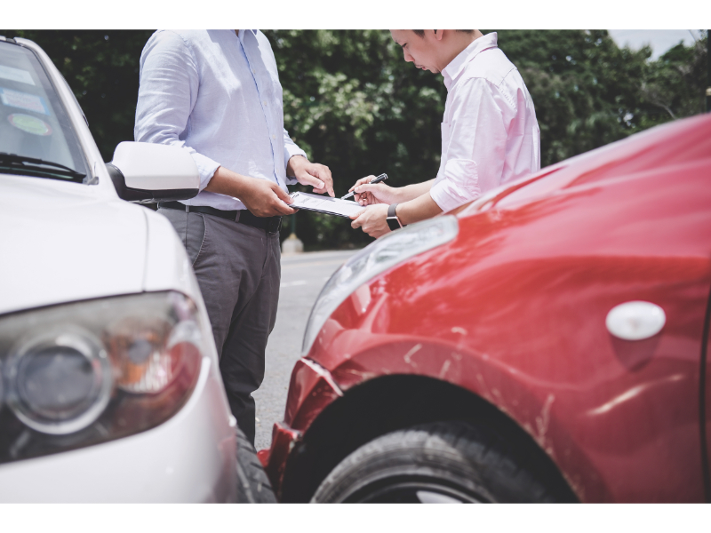 Two individuals exchanging insurance information after a car accident, inquiring about how long after an accident they can claim an injury.