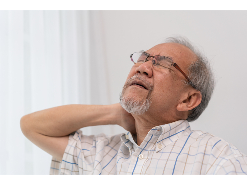 Elderly man feeling neck and lower back pain after an accident, possibly from tension or discomfort, while looking upwards with a strained expression.