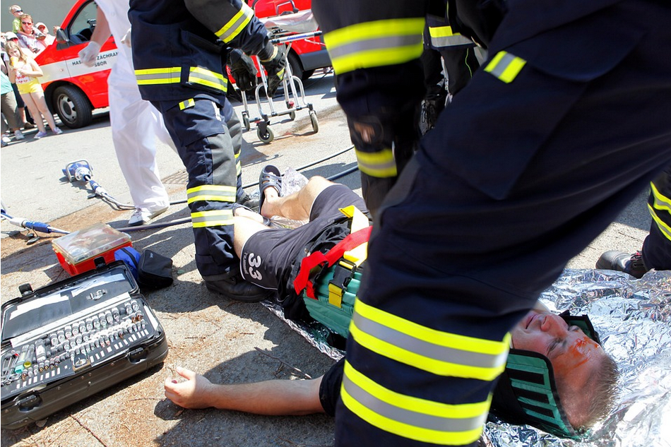 a fireman laying on the ground next to a fireman.