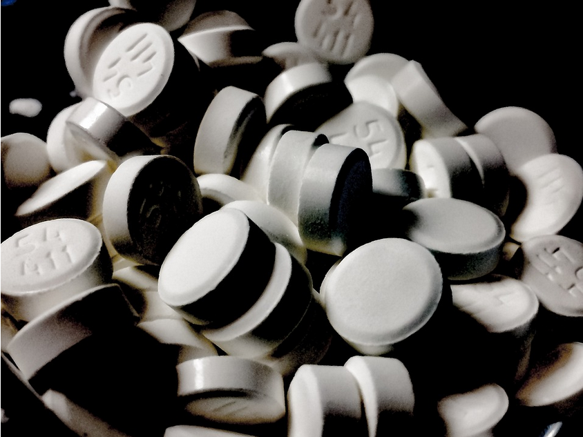 A pile of white and black pills used for auto accident injury.