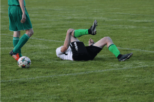 a man laying on the ground with a soccer ball.