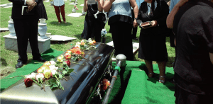 a group of people standing around a black casket.
