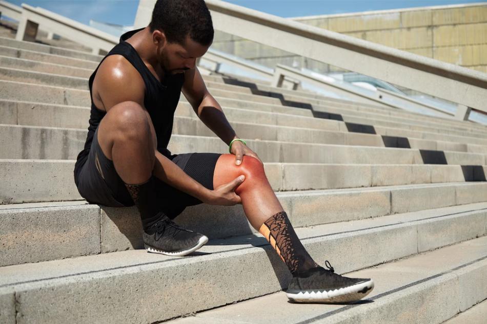 A man with a knee injury sitting on the steps.