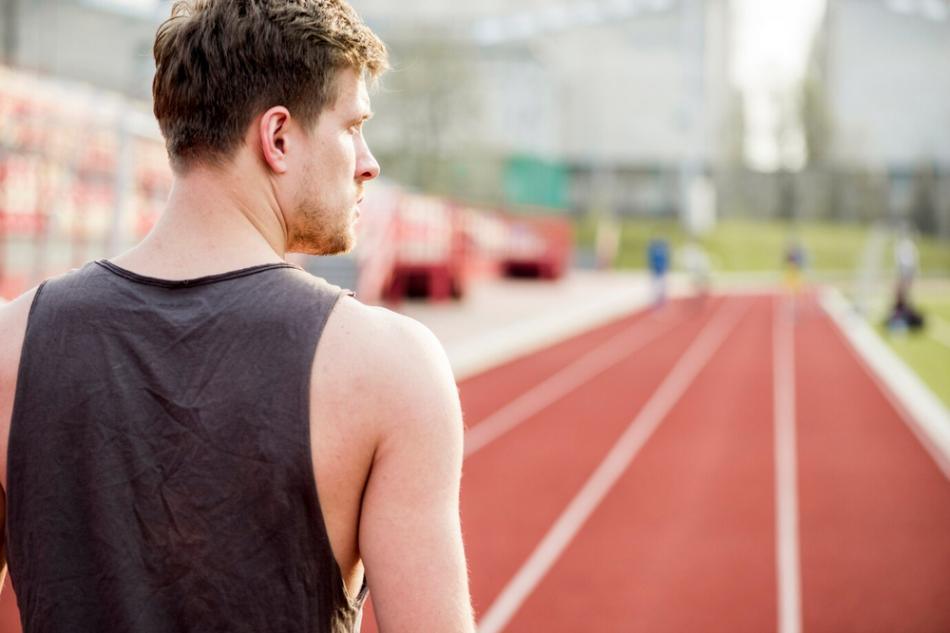 a man standing on a running track, potentially susceptible to sports injuries.