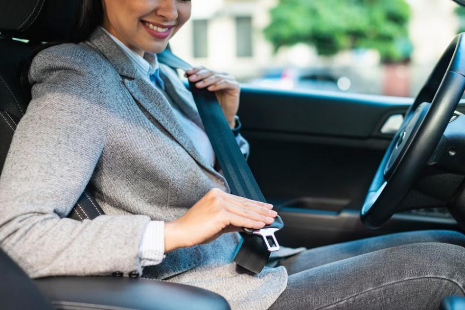 A woman wearing a seatbelt inside a car involved in a rideshare accident.