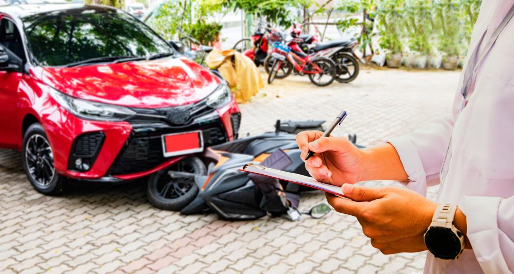 A person in a white coat writes on a clipboard in the foreground. In the background, a red car is parked next to a fallen motorcycle, likely involved in uninsured motorist claims, with several other motorcycles and greenery visible in the distance.