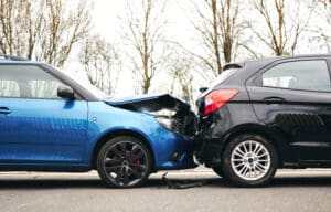 Two cars involved in traffic accident on side of the road with damage to bonnet and fender