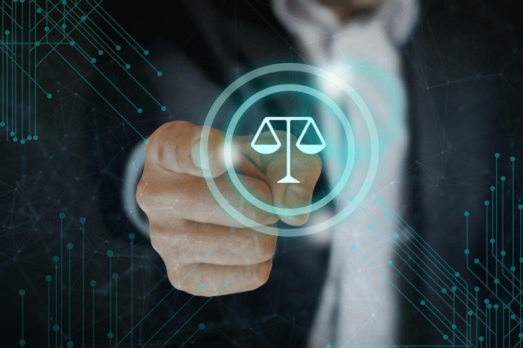 A person in a suit points towards a digital depiction of scales of justice within a glowing circular interface, surrounded by abstract circuit patterns, symbolizing law and technology integration.