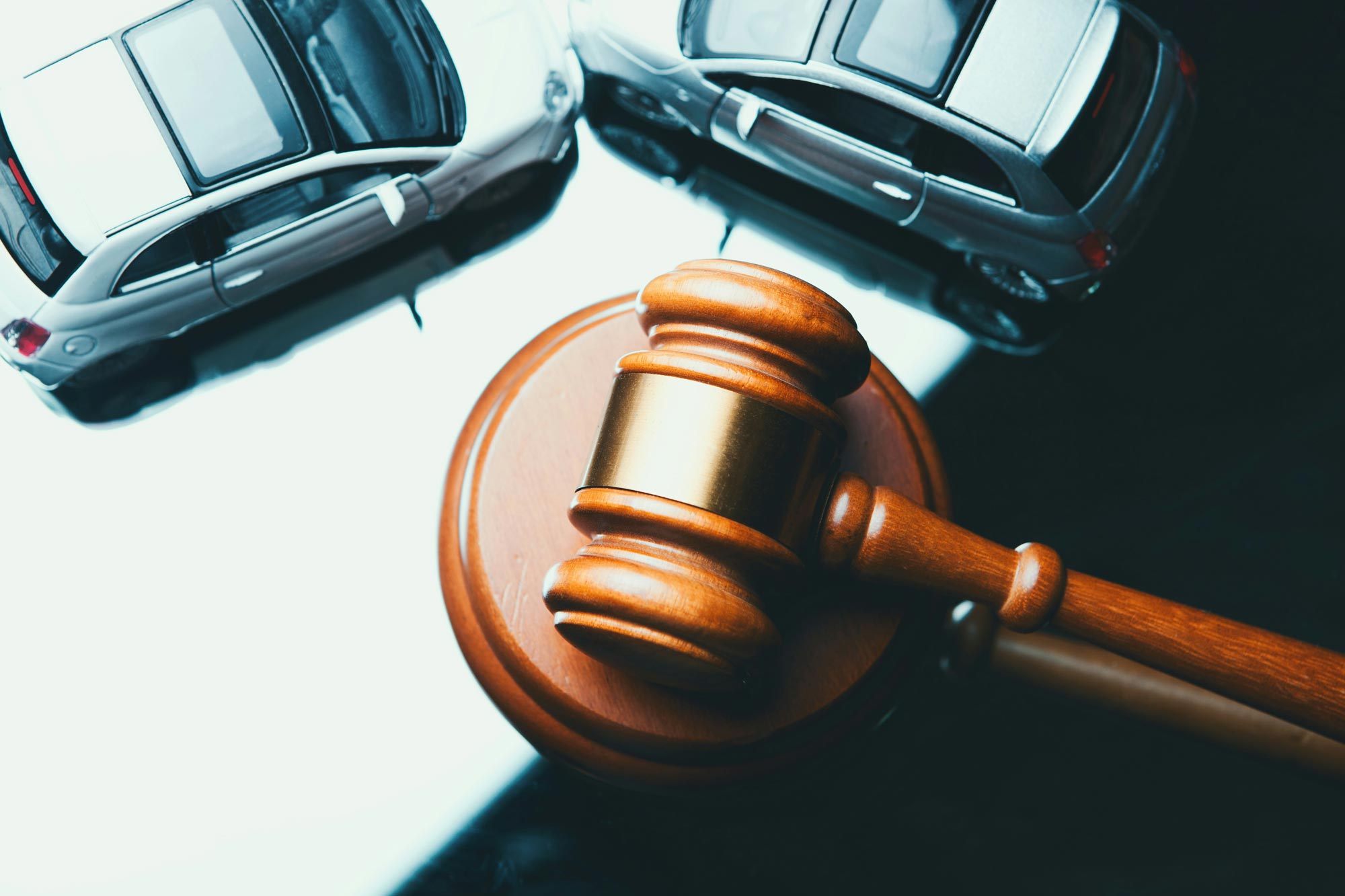 Judge's gavel next to two cars, symbolizing legal proceedings related to a car accident or traffic dispute
